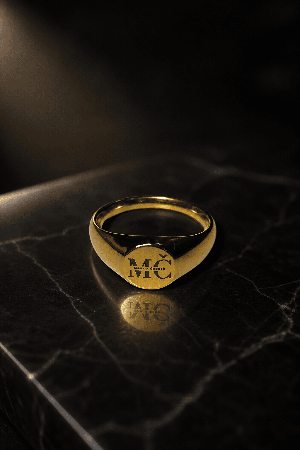 Gold MČ ring on a black marble surface