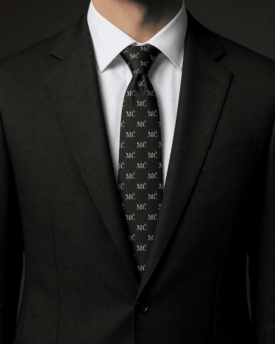 Black MČ monogram tie worn with a black suit